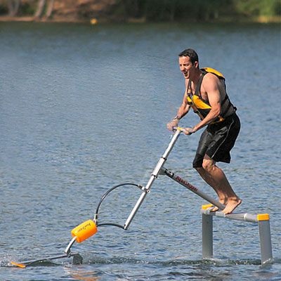 Um homem praticando o esporte aquaskipper no lago, indo em direção ao lado esquerdo da imagem.